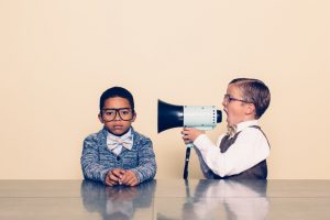 Boy yells through megaphone at another boy sitting next to him